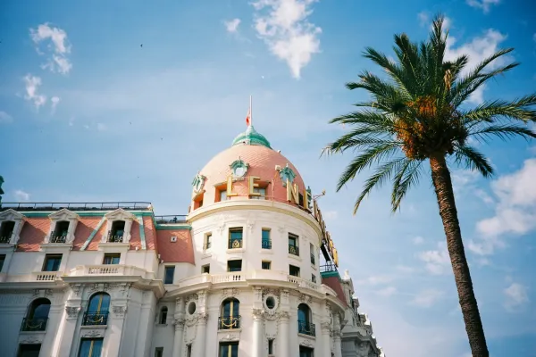 Iconic Negresco Hotel in Nice, featuring Belle Époque architecture and palm trees under a blue sky