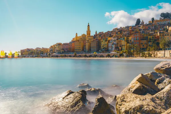 Seaside view of Menton with historic bell tower and calm sea, French Riviera