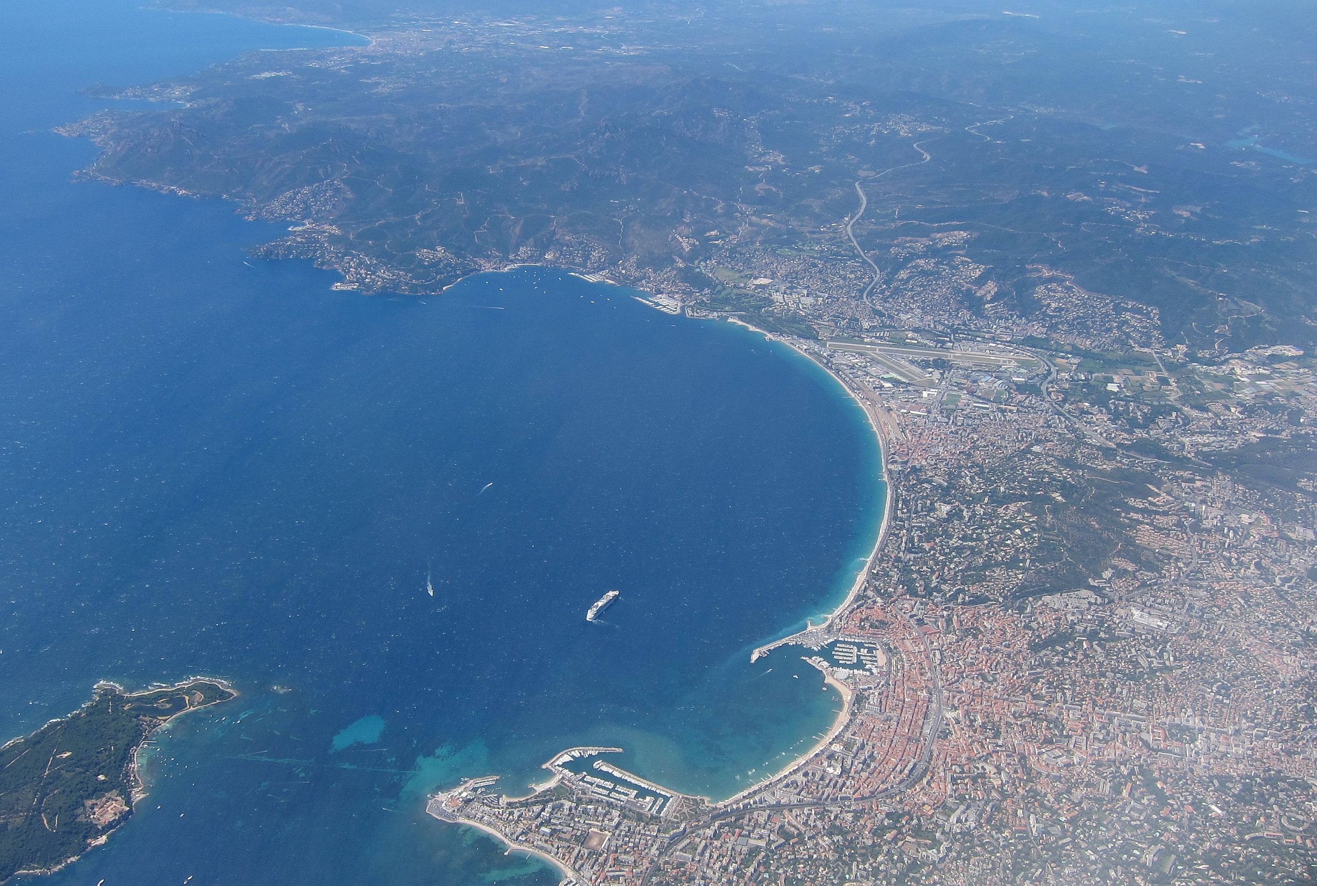 Cannes vs. Nice: Which Côte d’Azur City Should You Visit?, Aerial view of Cannes Bay and French Riviera coastline with mountains in the background
