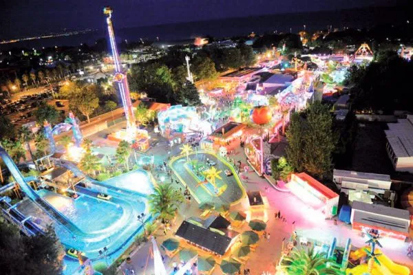 Evening funfair with rides and games by the sea Colorful amusement rides at Antibes Land near the coast
