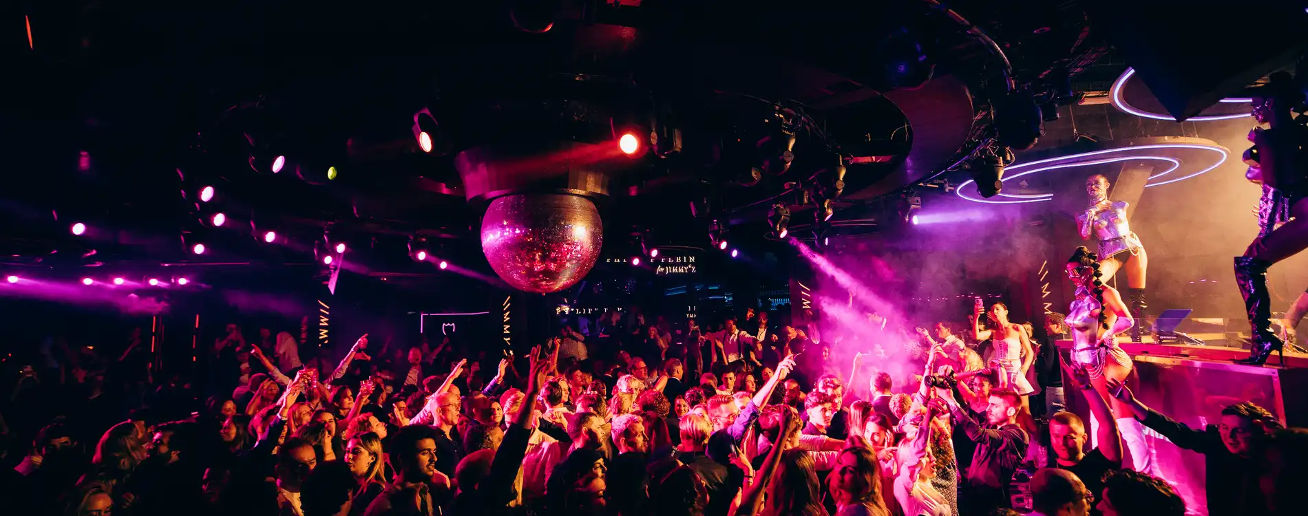 Experience high-end nightlife at Jimmy’z Monte-Carlo in Monaco Thrilling Nightlife on the French Riviera: Top 10+ Picks.. Two DJs perform at a luxury club with neon lights and a vibrant crowd in Monaco