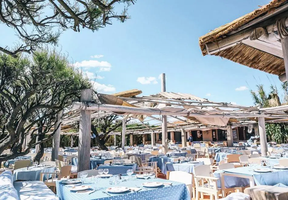 Le Club 55 – Iconic Beachfront Dining in Saint-Tropez Open-air dining setup at Le Club 55 with rustic wooden pergolas