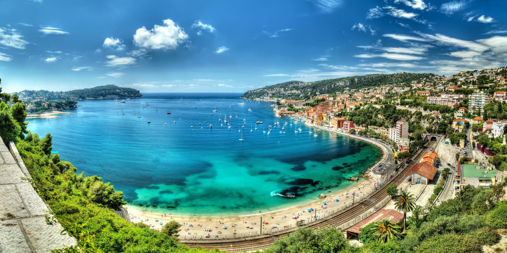 Panoramic photo of Villefranche-sur-Mer with turquoise bay, beach, and hillside homes