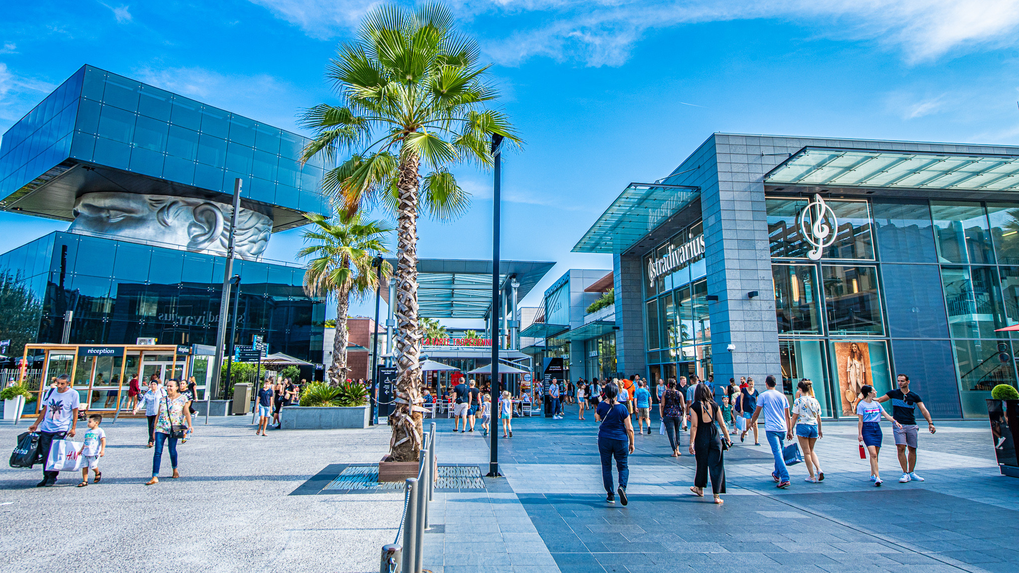 Polygone Riviera – Best Shopping & Dining in Cagnes-sur-Mer Outdoor shopping mall with palm trees and modern shops in Cagnes-sur-Mer