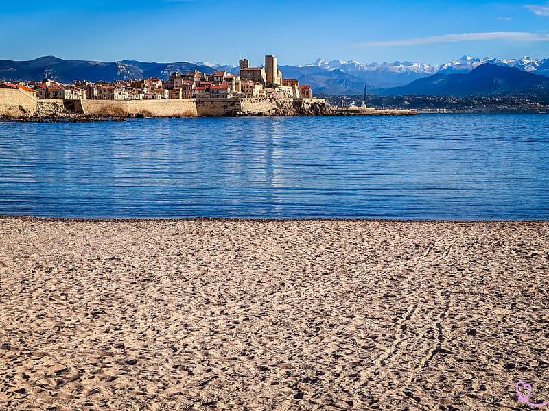 Golden-hour scene of a quiet sandy beach near Antibes with families enjoying the October sun