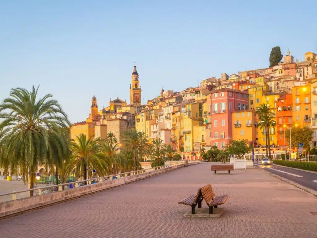 Pastel buildings in Menton with palm trees and a serene October sky