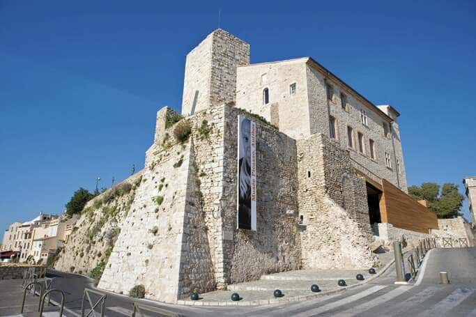 Families exploring a bright museum gallery with Mediterranean art and sea views