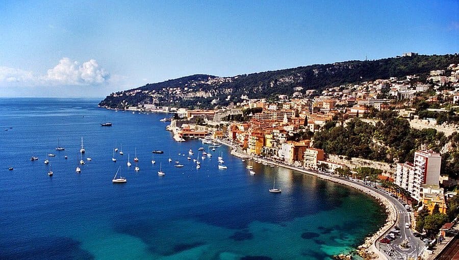 Parents and kids in light jackets strolling the Promenade des Anglais on a sunny October day