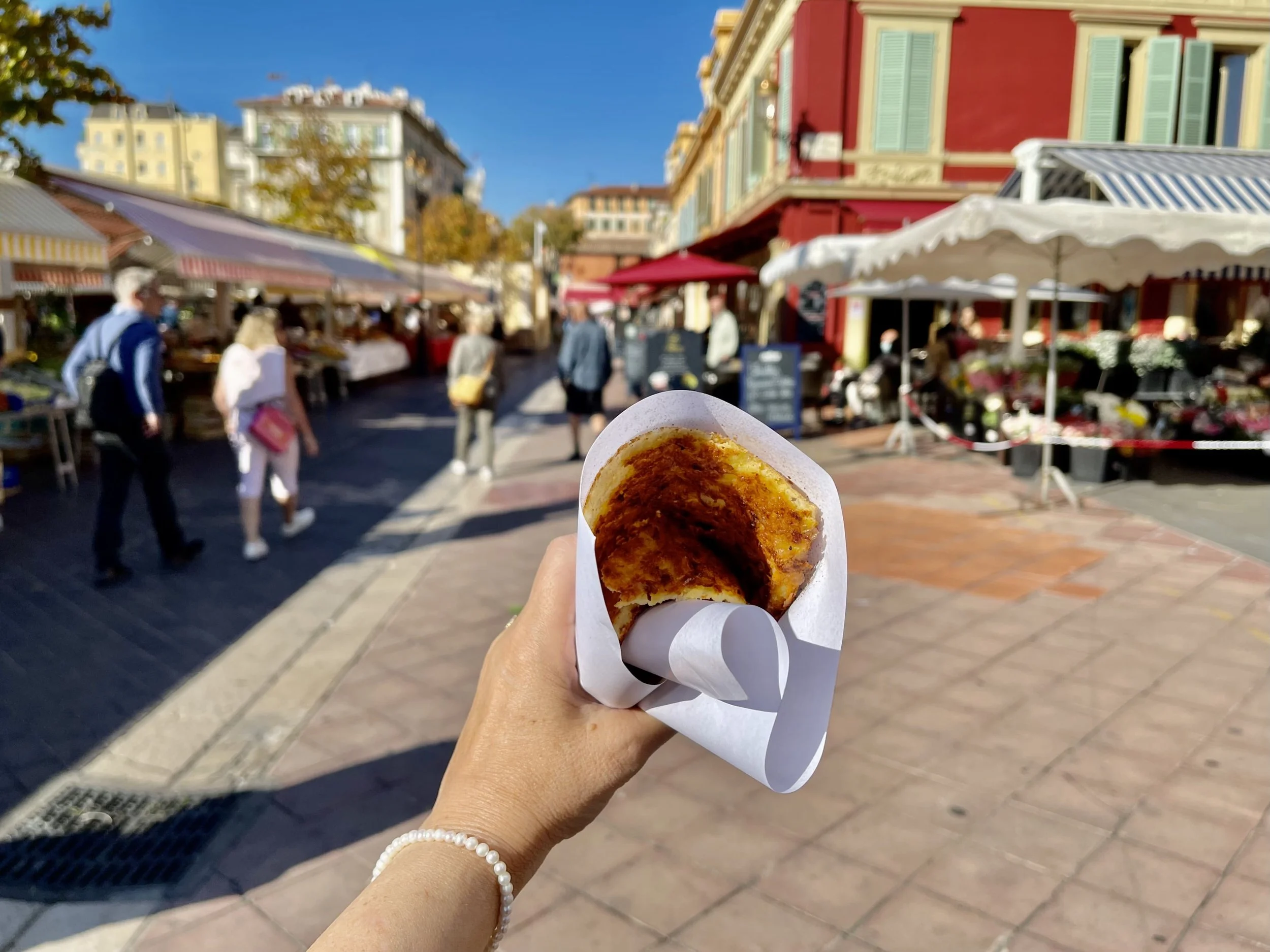 Close-up of socca being sliced on a wooden board in Nice’s old town